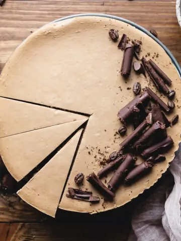 whole keto coffee cheesecake on a wooden table decorated with chocolate curls