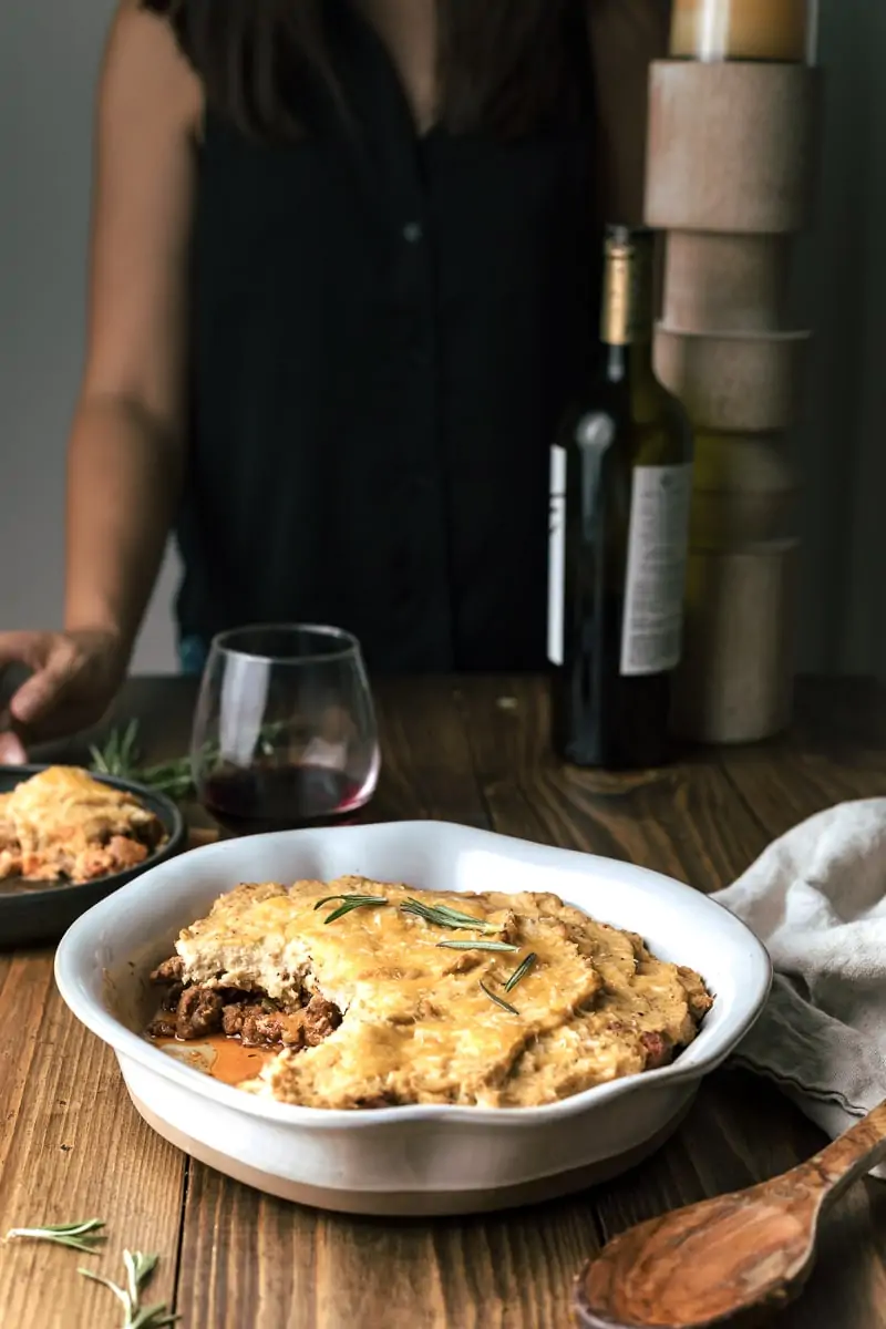 Keto shepherd's pie (cottage pie) with bottle of wine set at a table.