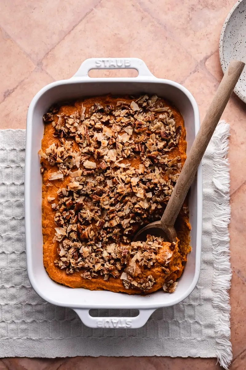 healthy sweet potato casserole in dish with wooden spoon