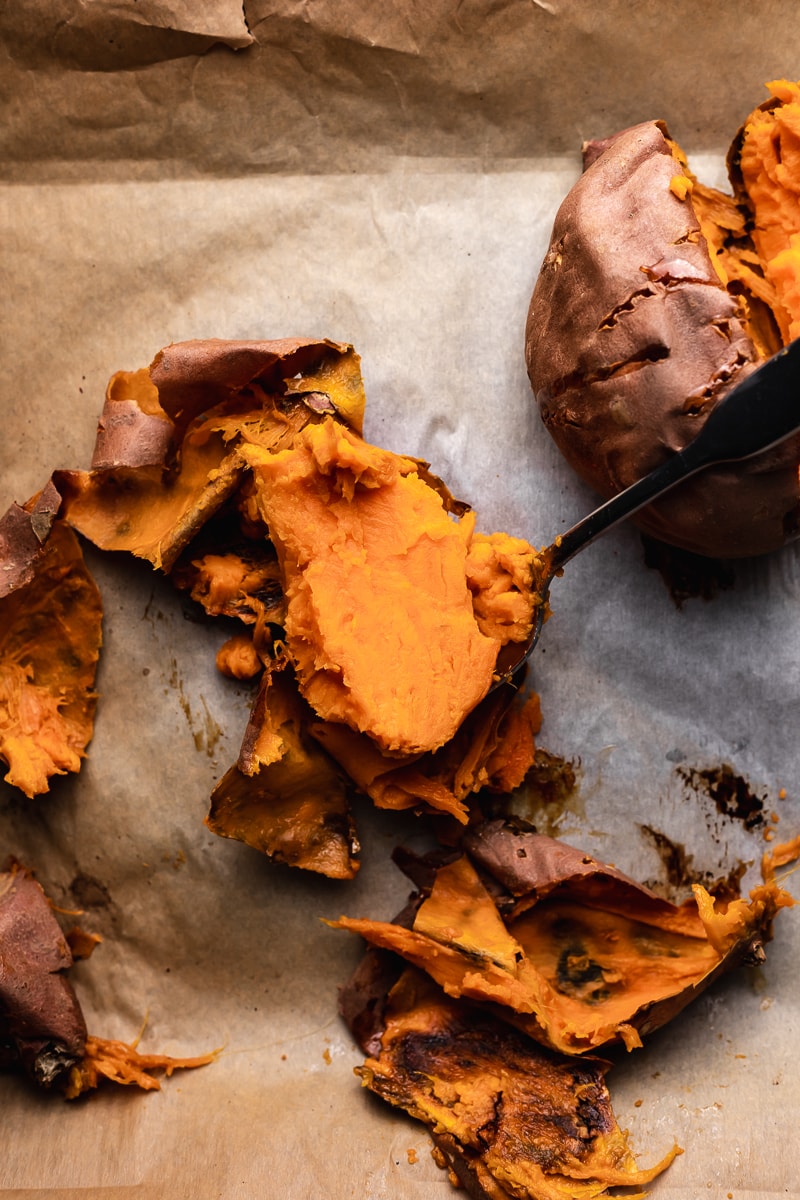 spoon scooping sweet potato away from skins