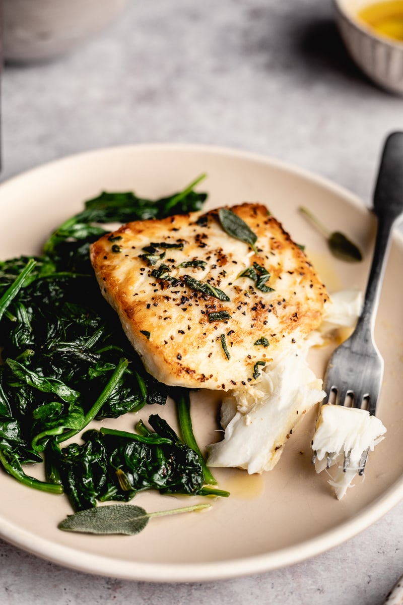 pan-seared halibut on a plate with a bite on a fork