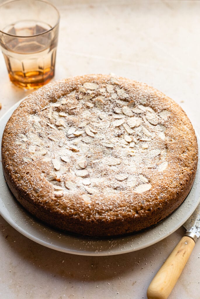 keto almond cake on a white plate with a tan glass