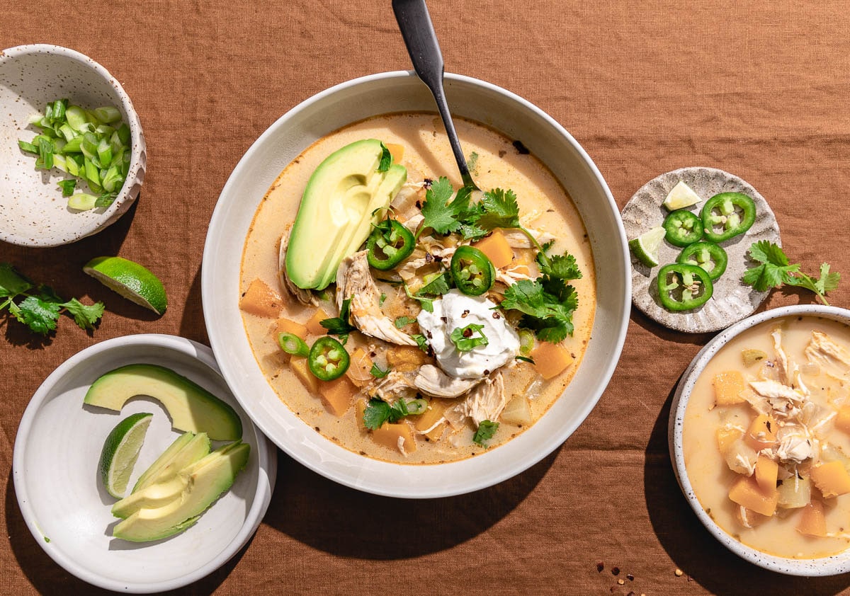 keto chicken chili in a bowl with avocado , sour cream and other toppings