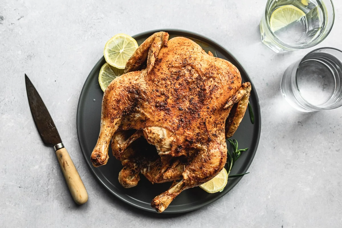air fryer whole chicken with lemon and water glasses