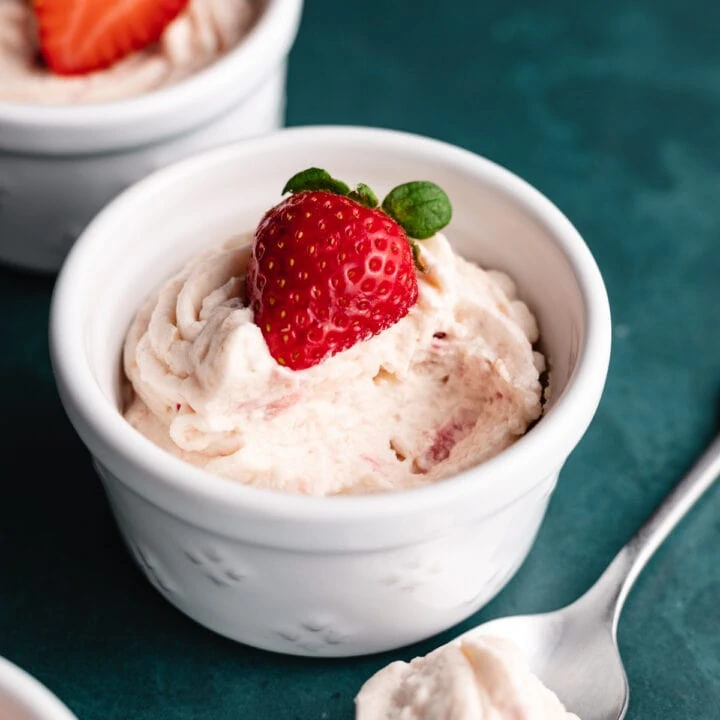 Closeup of keto strawberry mousse with a strawberry and a spoon.