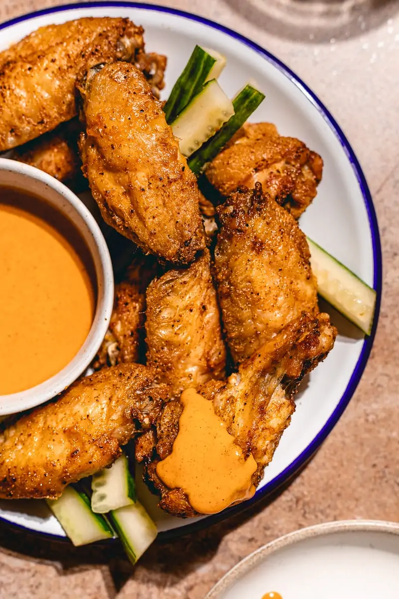 Closeup of crispy air fryer chicken wings with cucumber slices.