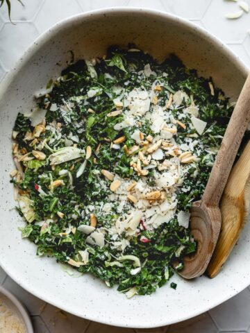 Bowl of copycat chick fil A kale salad with wooden serving spoons.