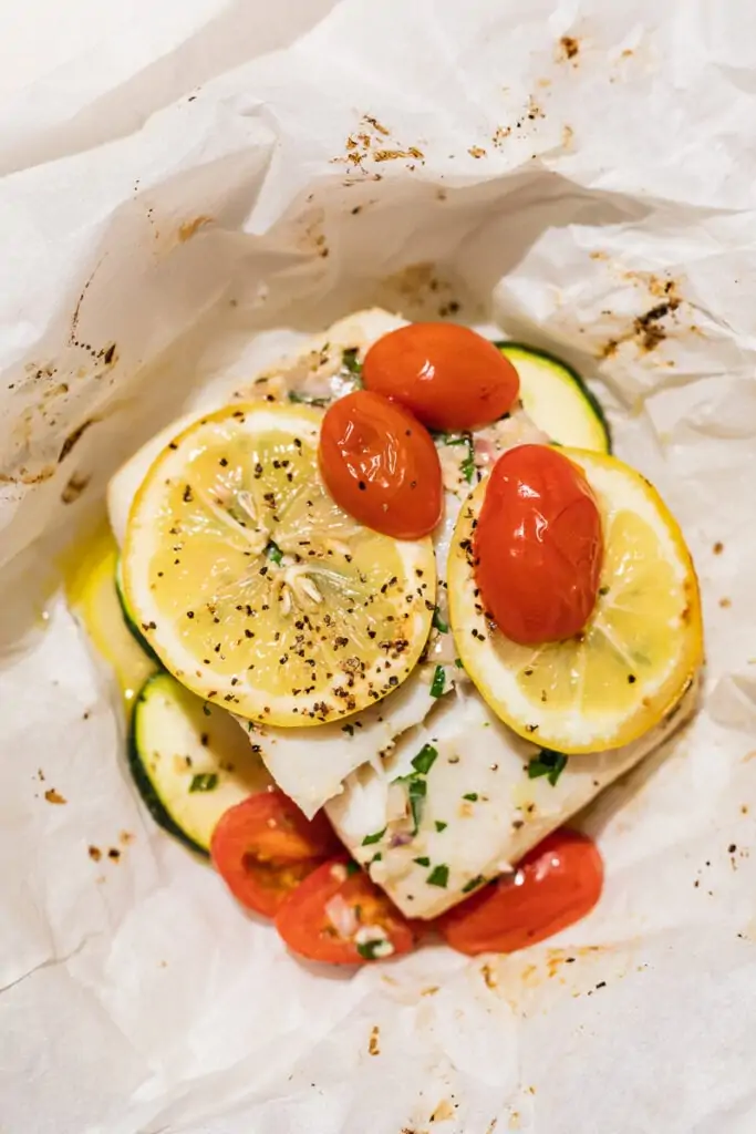 Closeup of lemon, pepper and tomatoes on top of a serving of air fryer halibut.