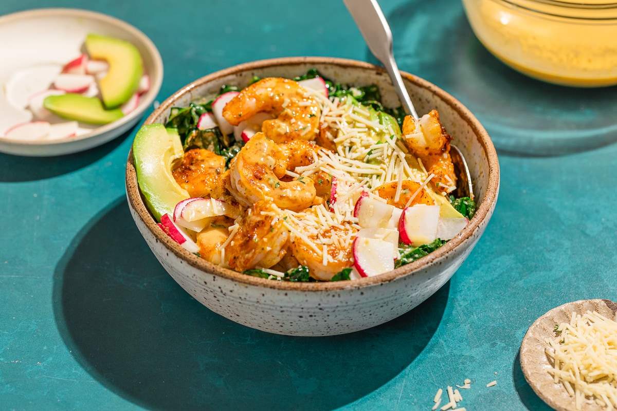 Cajun shrimp salad on a turquoise background with a spoon.