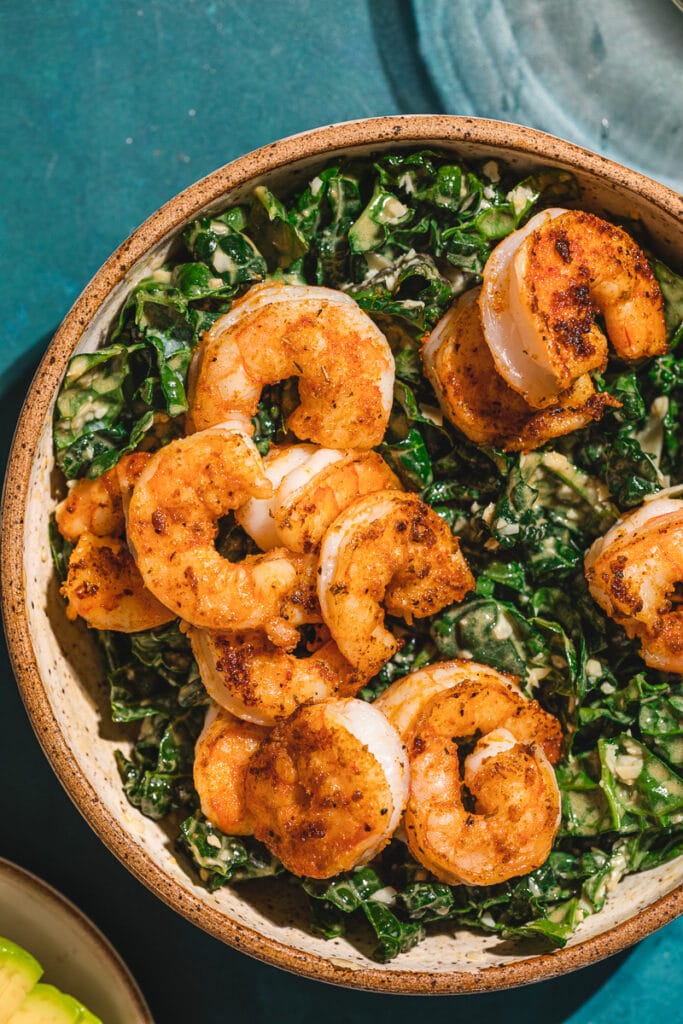 Cajun shrimp on top of a bed of kale with Caesar dressing.