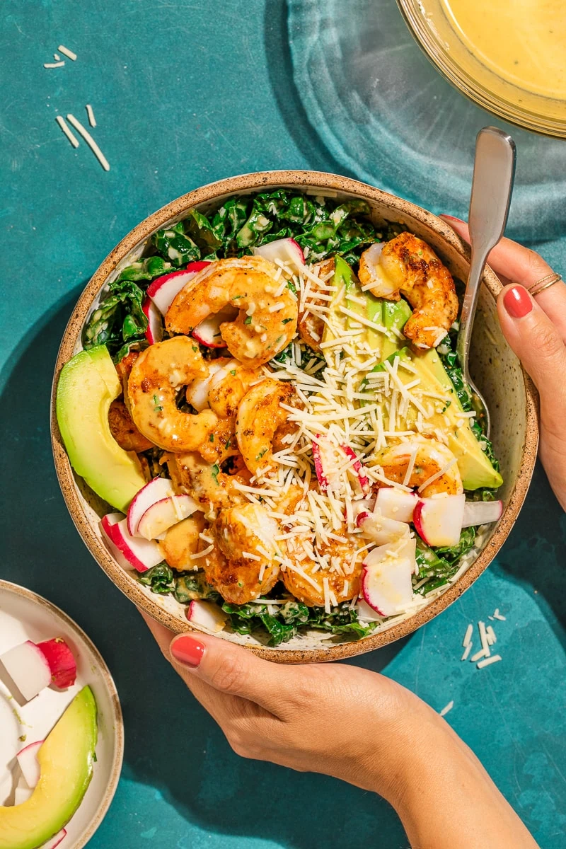 Overhead shot holding a bowl of kale cajun shrimp salad