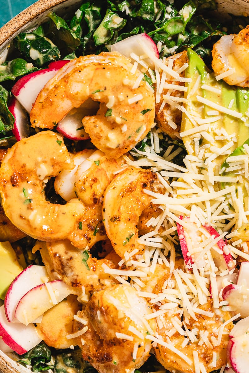 Closeup of cajun shrimp and parmesan on top of a bed of kale.
