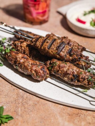 Closeup of ground beef kabobs on platter.