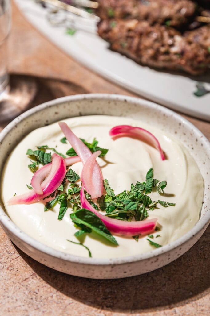 Whipped feta in a bowl with pickled onions and chopped mint.
