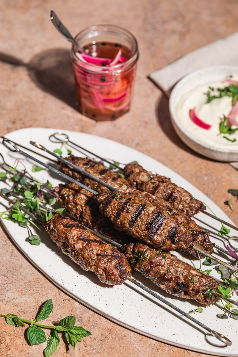 Mediterranean ground beef kebabs (koftas) on a white serving platter.