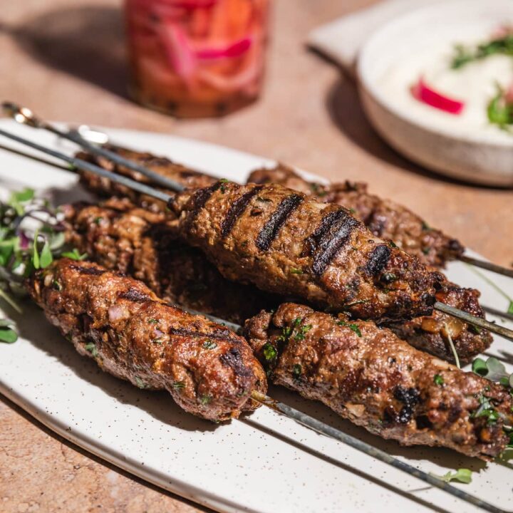 Mediterranean ground beef kabobs on skewers on a platter.