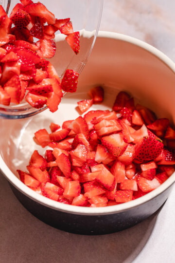 Pouring chopped strawberries into saucepan.