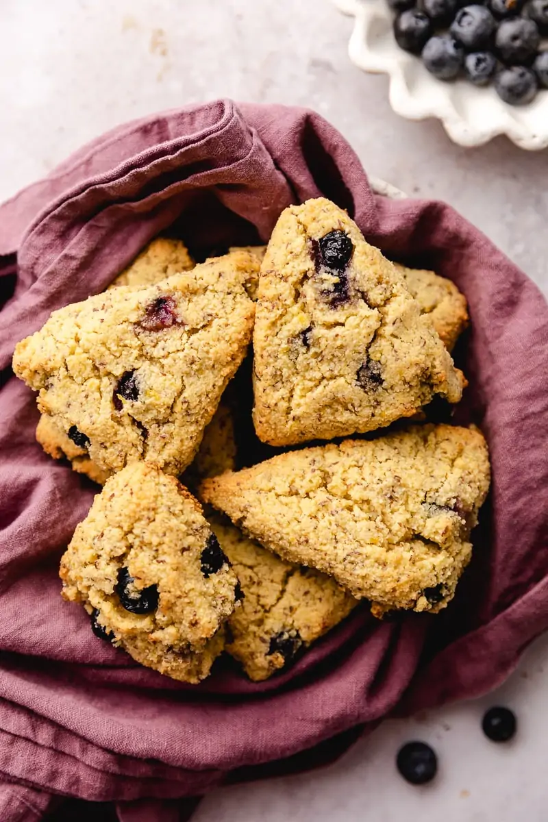 Overhead shot of keto scones on a purple linen with blueberries.