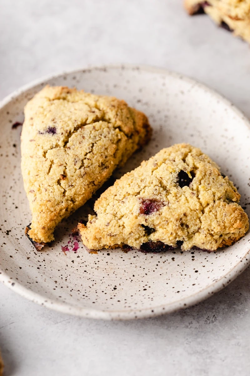 Two keto lemon blueberry scones on a speckled plate.