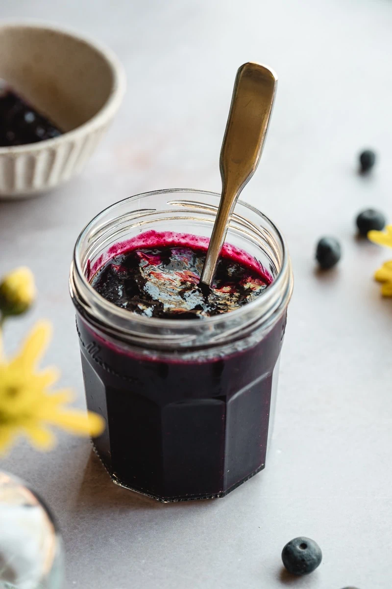 Sugar-free blueberry jam in a jam jar with a silver spoon.