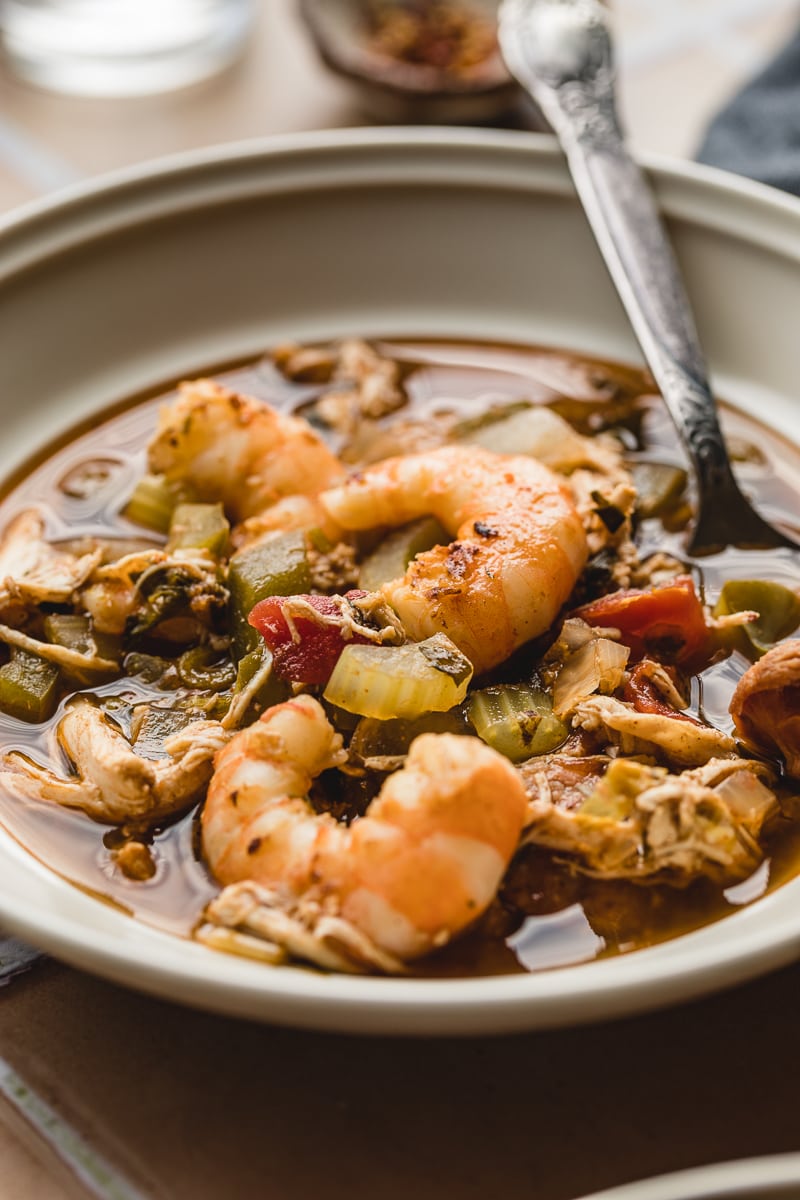Shrimp in a bowl of keto gumbo with a silver spoon.