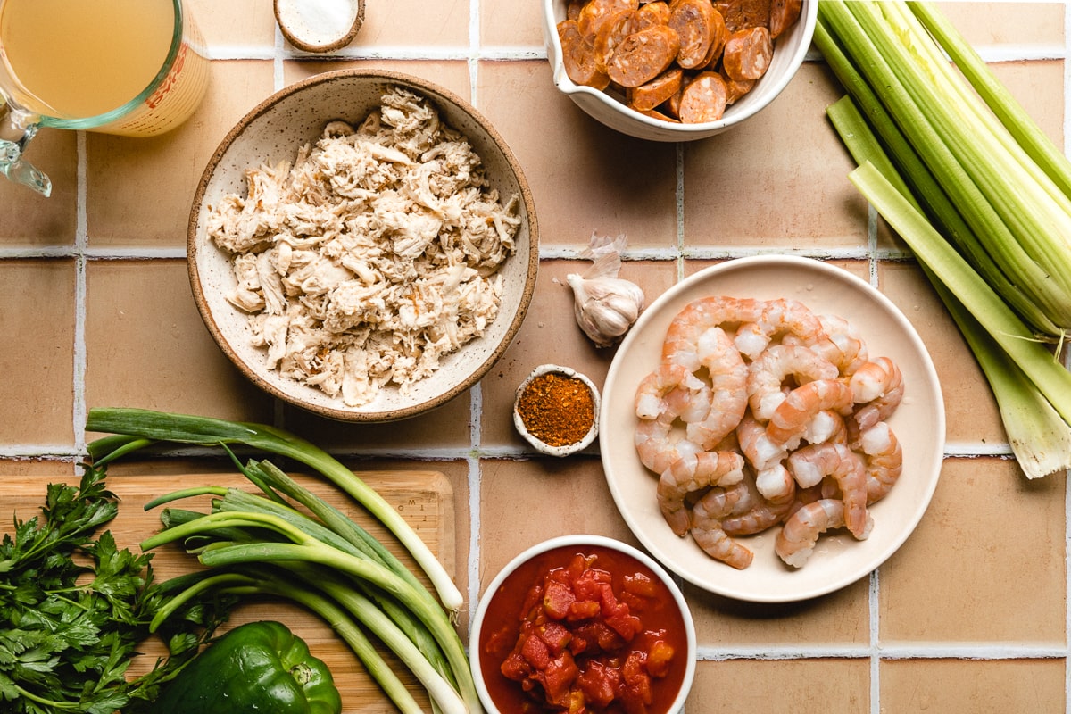 Ingredients for keto gumbo arranged in a flat lay on a tile surface for keto gumbo recipe.