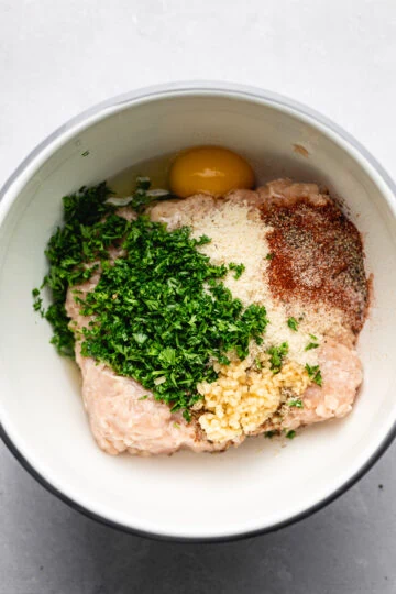Ingredients in a bowl for Greek chicken meatballs.