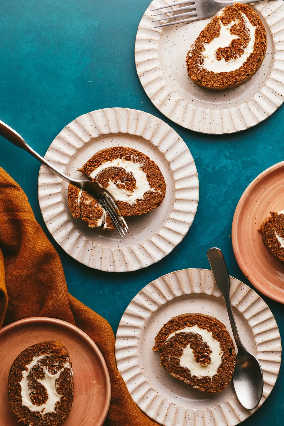 Gluten free pumpkin roll slices on plates with forks.