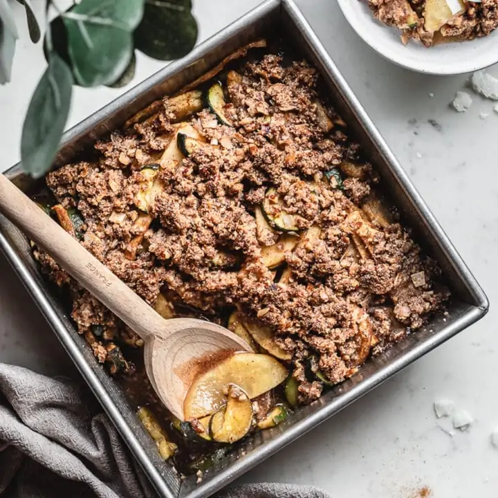 Low-carb apple crisp in a baking dish with a wooden spoon.