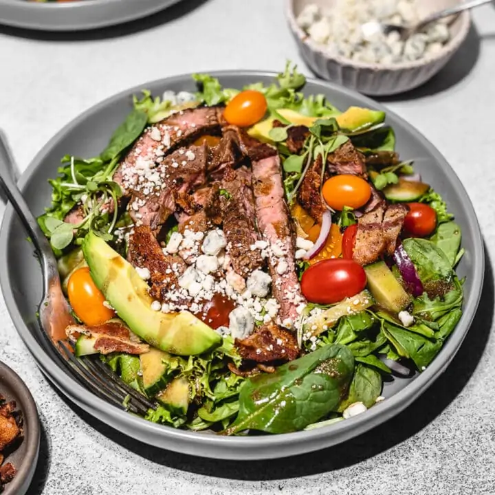 Keto steak salad on a gray plate with blue cheese crumbles.