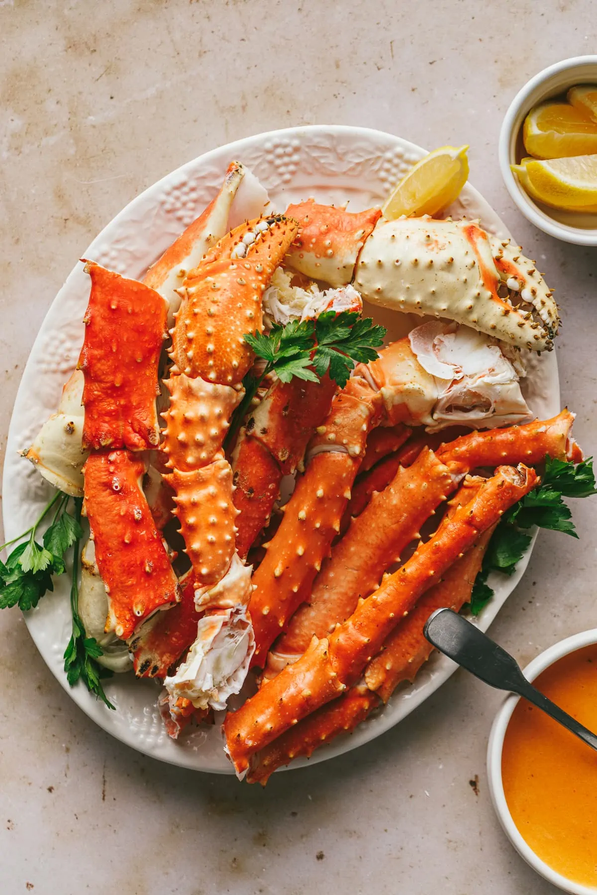 King crab legs and claws on a beige marble backdrop.
