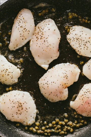 Halibut cheeks cooking in a pan.