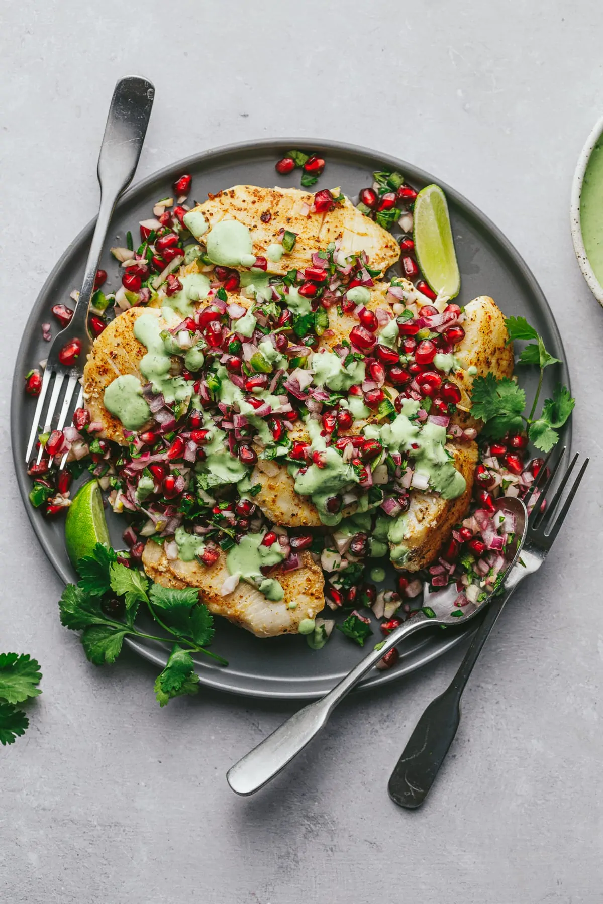 Halibut cheeks with pomegranate salsa on a gray serving plate.