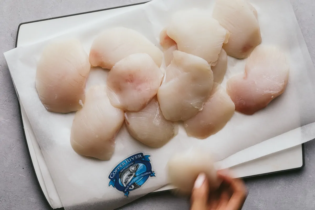 Placing halibut cheeks on a cutting board.