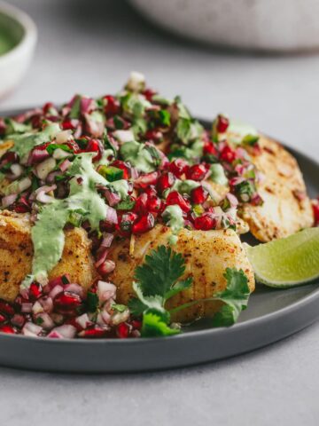 Halibut cheeks with pomegranate salsa on a platter with garnishes.