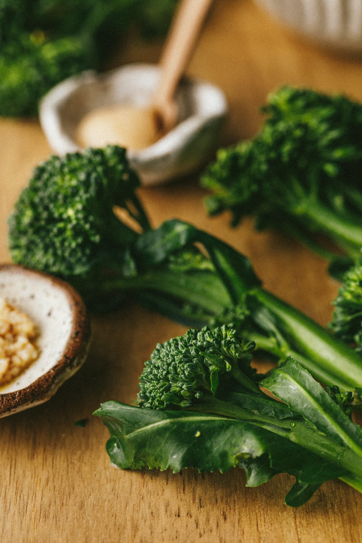 Broccolini on cutting board next to minced garlic.