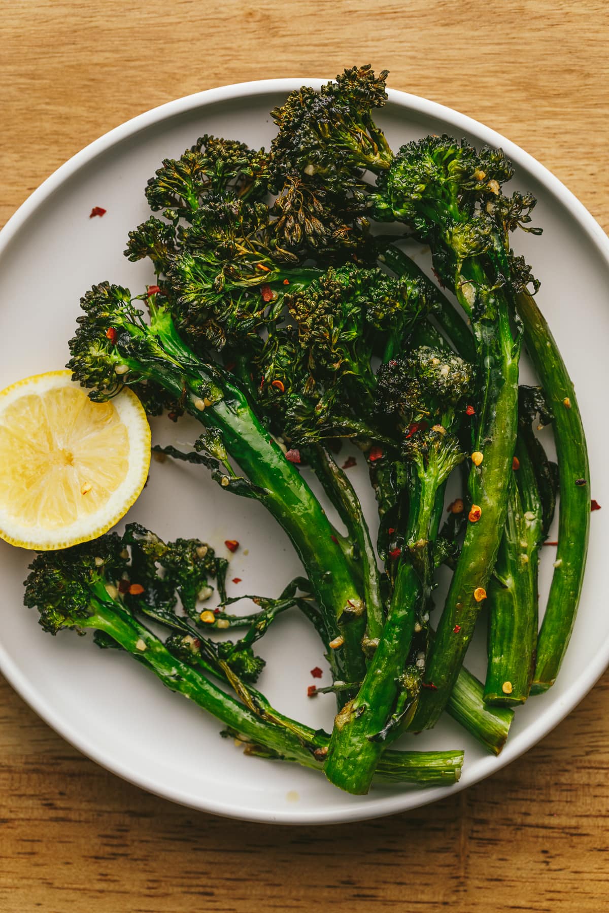 Air fryer broccolini on a white plate with lemon.