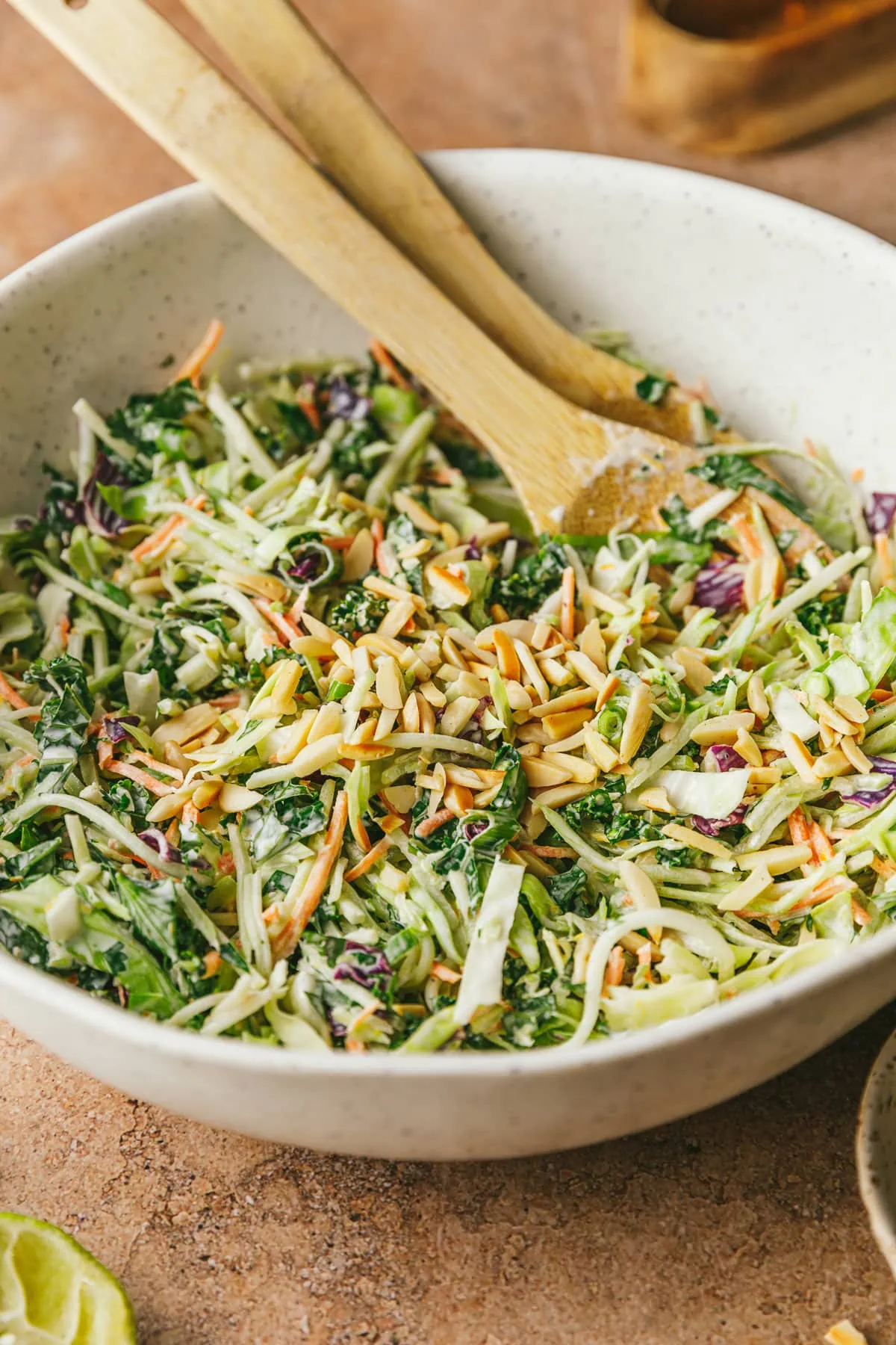 Citrus slaw in a white bowl with wooden spoons.