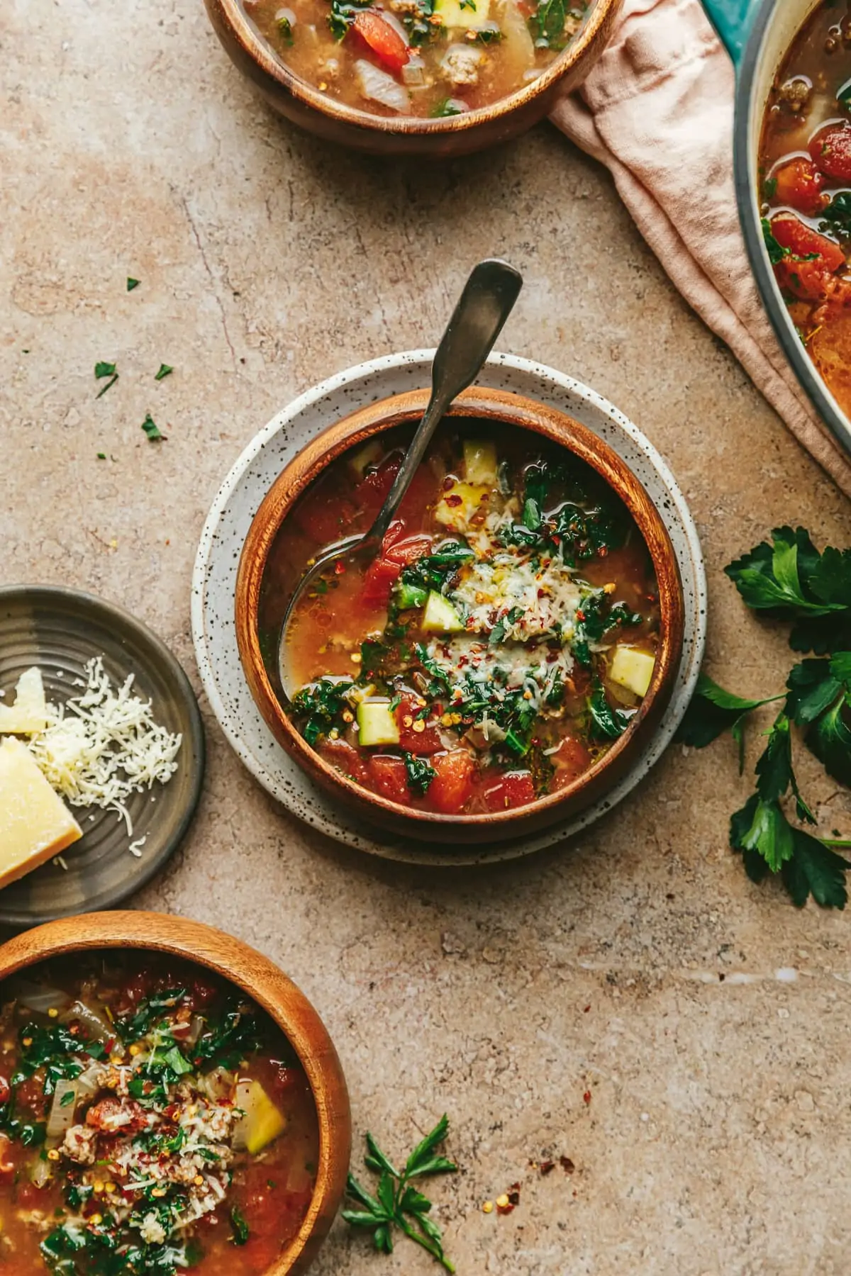 Wooden bowls of keto Tuscan soup on a brown marble counter.