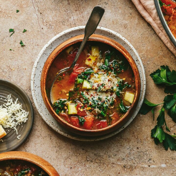 Keto Tuscan soup in a wooden bowl with a spoon and garnishes.
