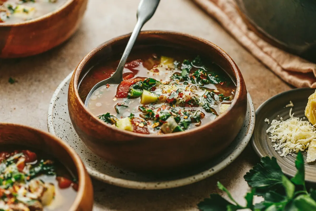 Keto Tuscan soup in a wooden bowl backlit.