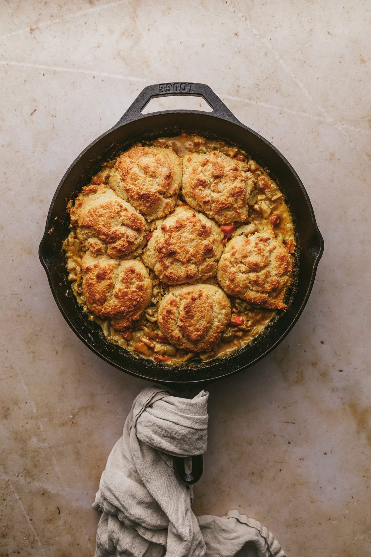 Keto chicken pot pie with biscuits in a black skillet on a marble counter.