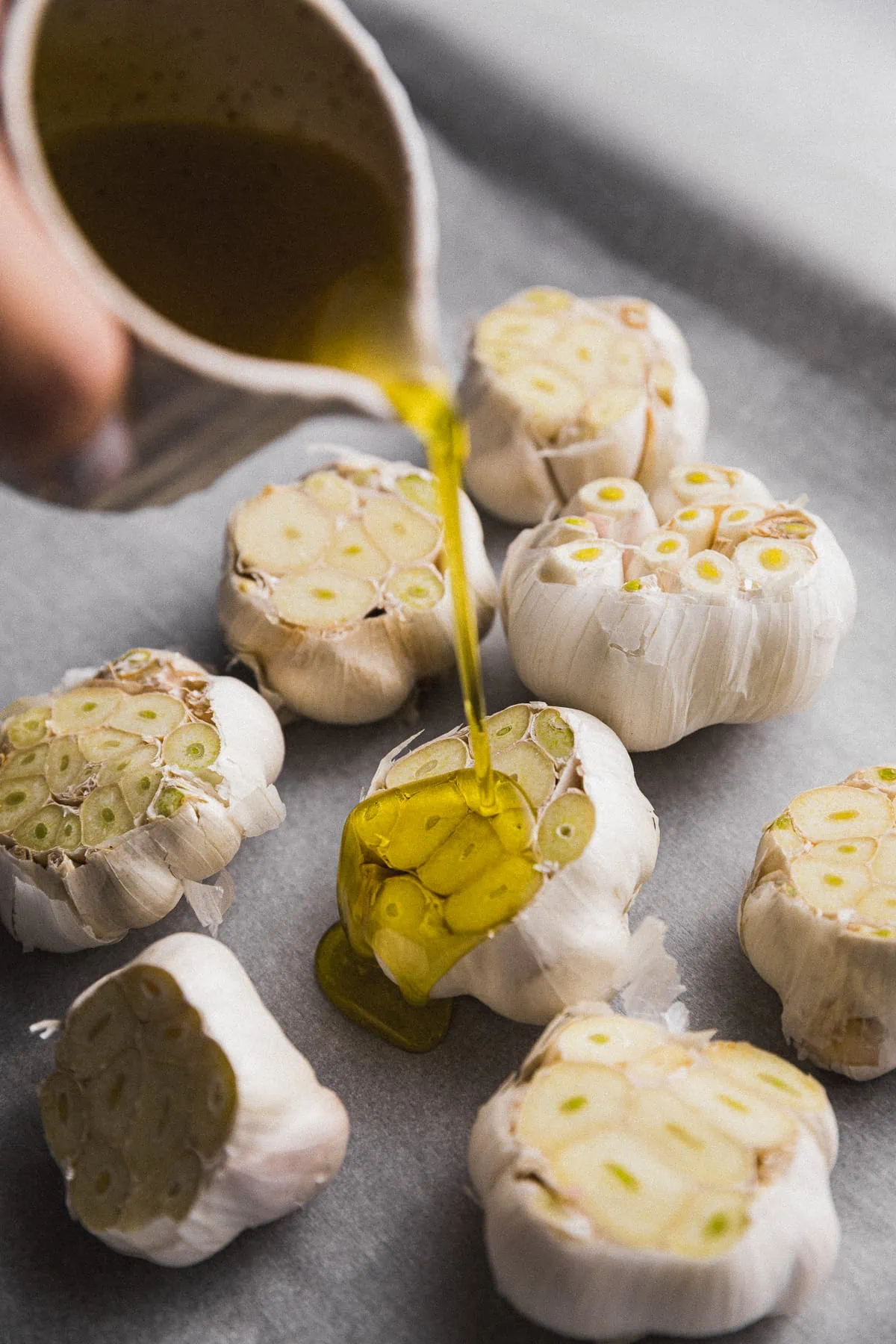 Pouring olive oil onto raw garlic clove.