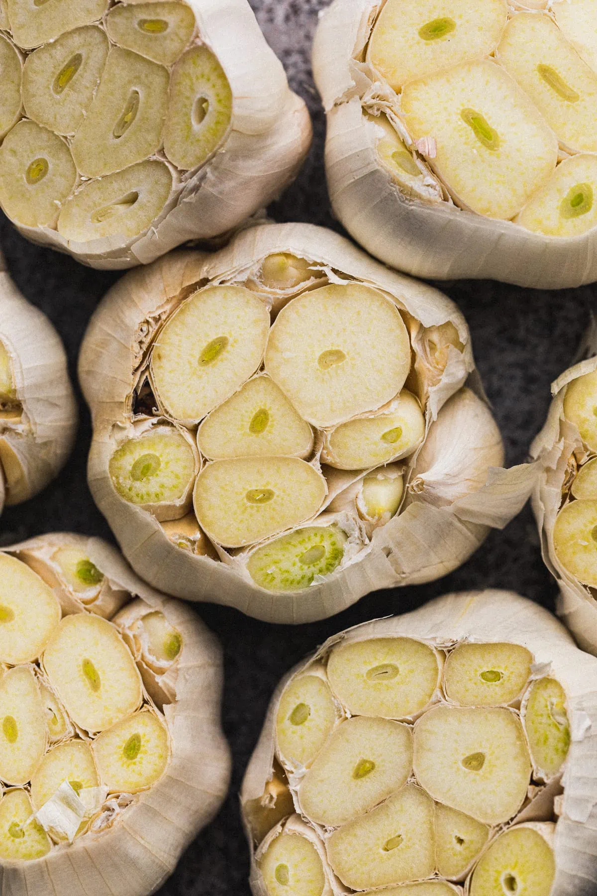 Raw heads of garlic with tops sliced off.