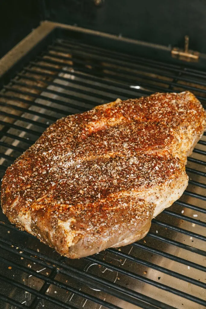 Chuck roast covered in dry rub on a Traeger grill grate.