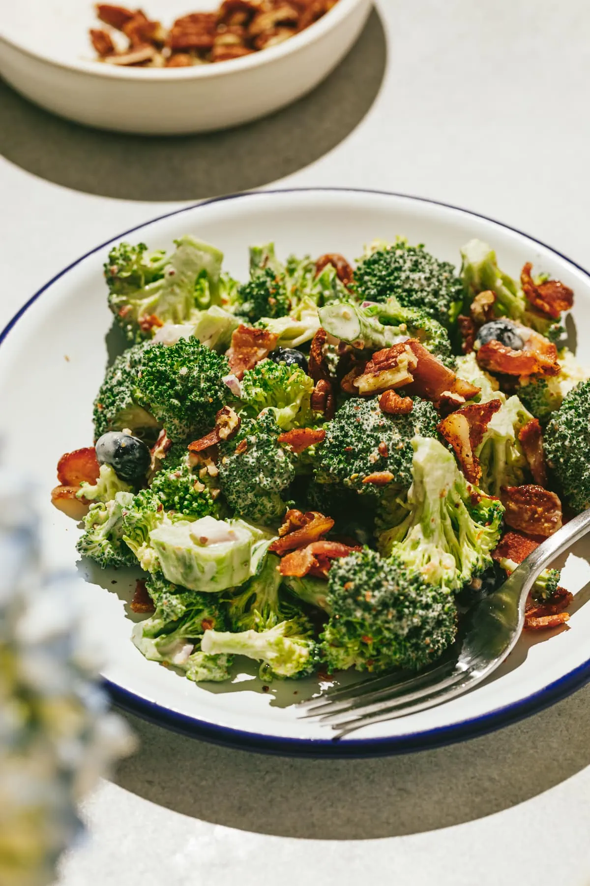 Broccoli crunch salad on a blue-rimmed plate with a fork.