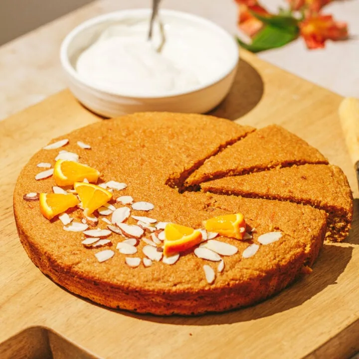 A whole gluten-free orange almond cake on a cutting board.