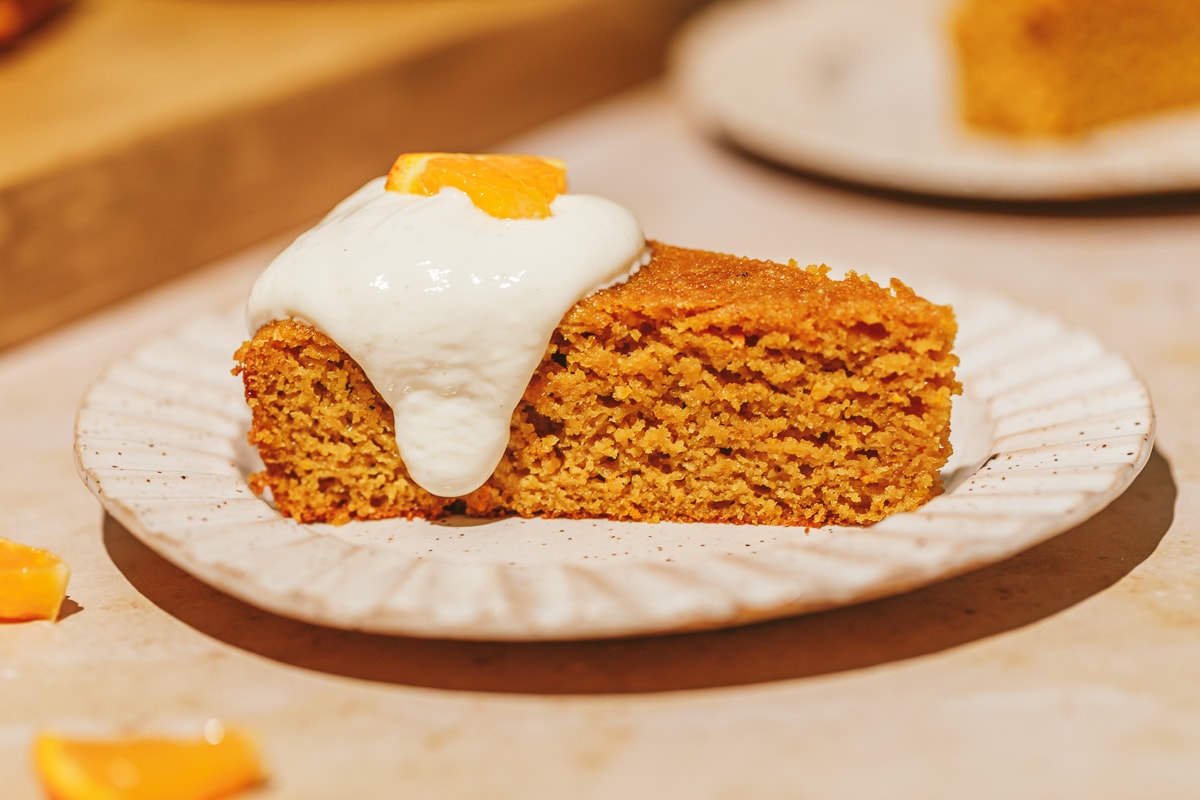A slice of gluten-free orange cake with Greek yogurt cardamom topping.