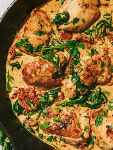 Keto Tuscan chicken in a skillet with fresh parsley.