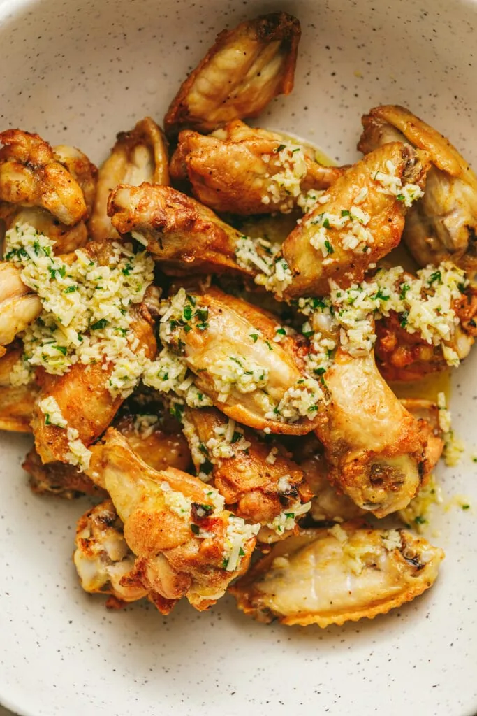 Low carb chicken wings being tossed in garlic parmesan sauce.